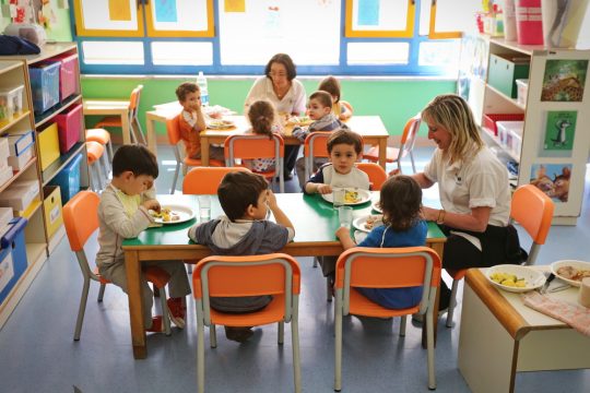 Une ATSEM supervisant le repas de jeunes enfants à l'école maternelle.