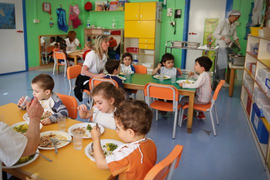 Une ATSEM en compagnie de tout-petits à l'école maternelle.