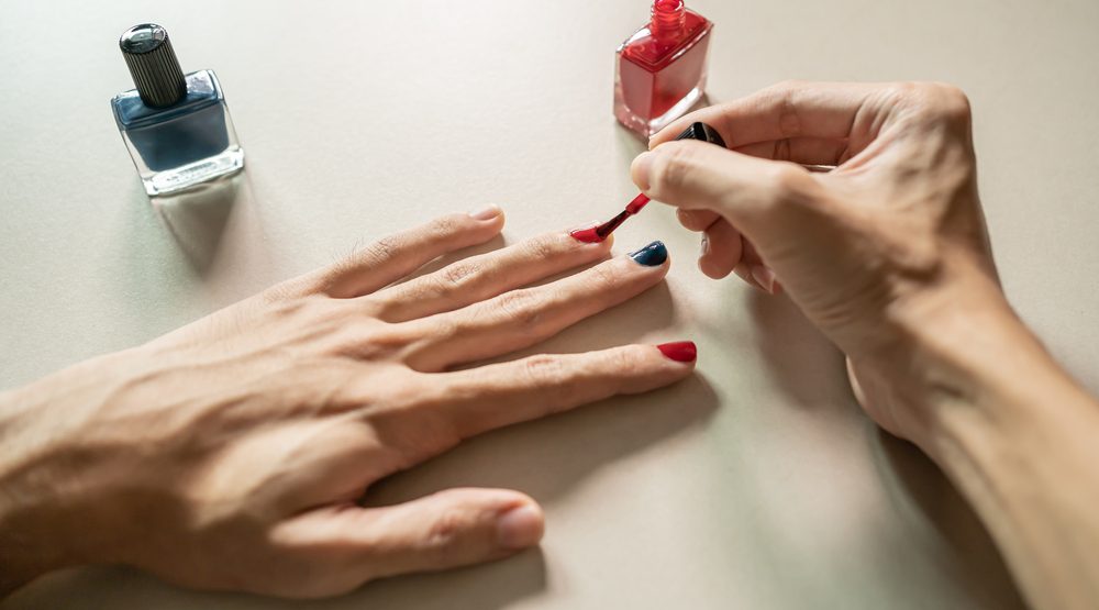 homme peignant ses ongles avec du vernis